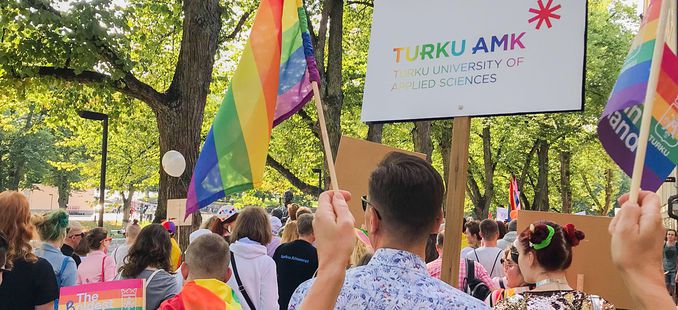 Pride parade in Turku, rainbow flag and Turku UAS logo in rainbow color